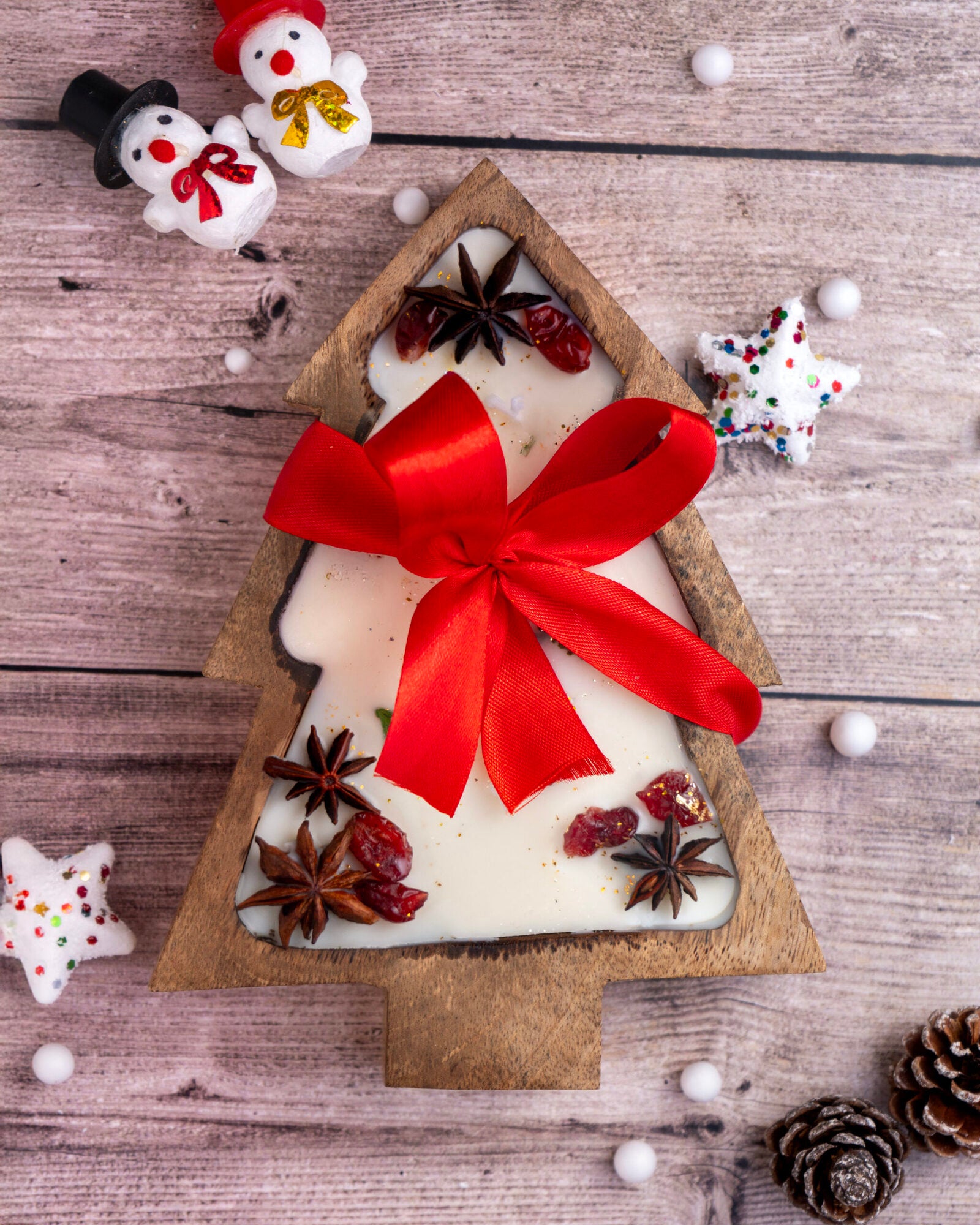 Christmas tree candle in a wooden bowl, adorned with cranberries and greenery, perfect for cozy holiday decor.