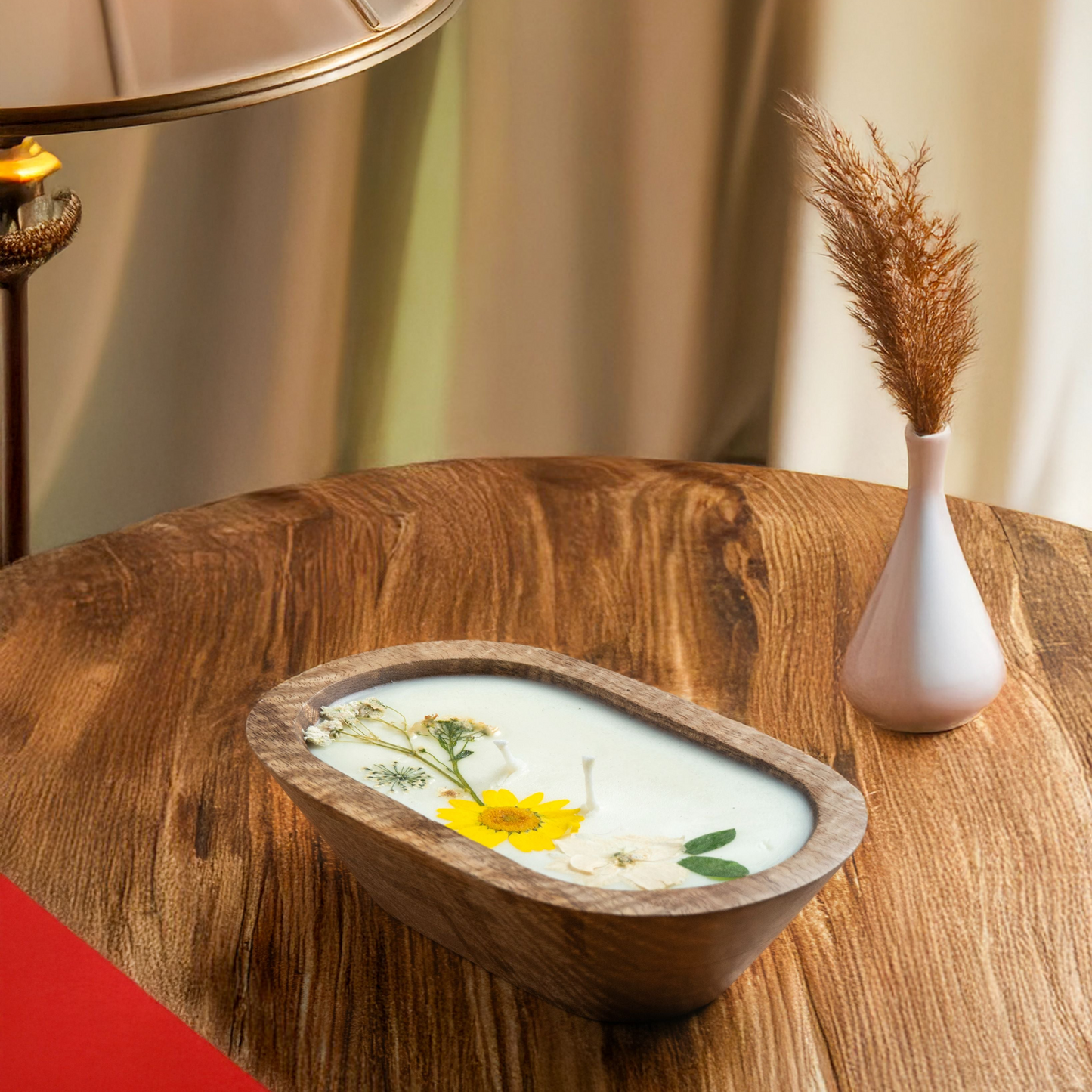 Wooden bowl with floral design on a wooden table next to a lamp and vase.