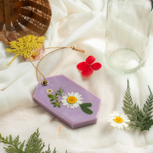 Purple decorative tag with pressed flowers on a white fabric background
