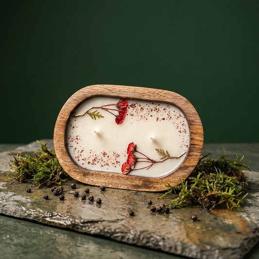 Candle in a wooden holder with dried flowers on a stone surface with a green background