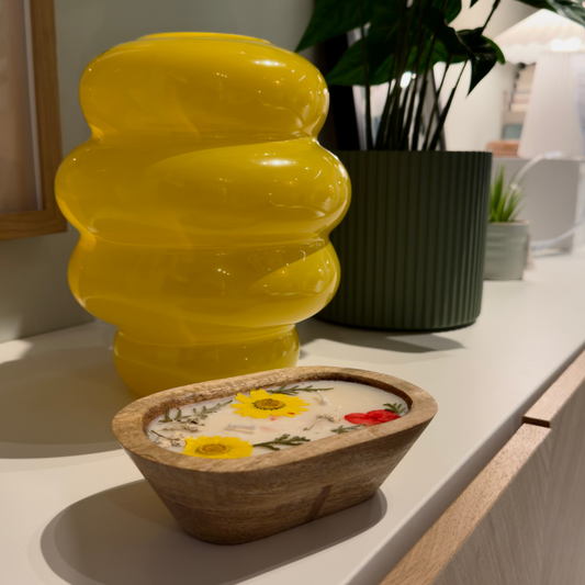 Wooden bowl candle with floral design on a light surface