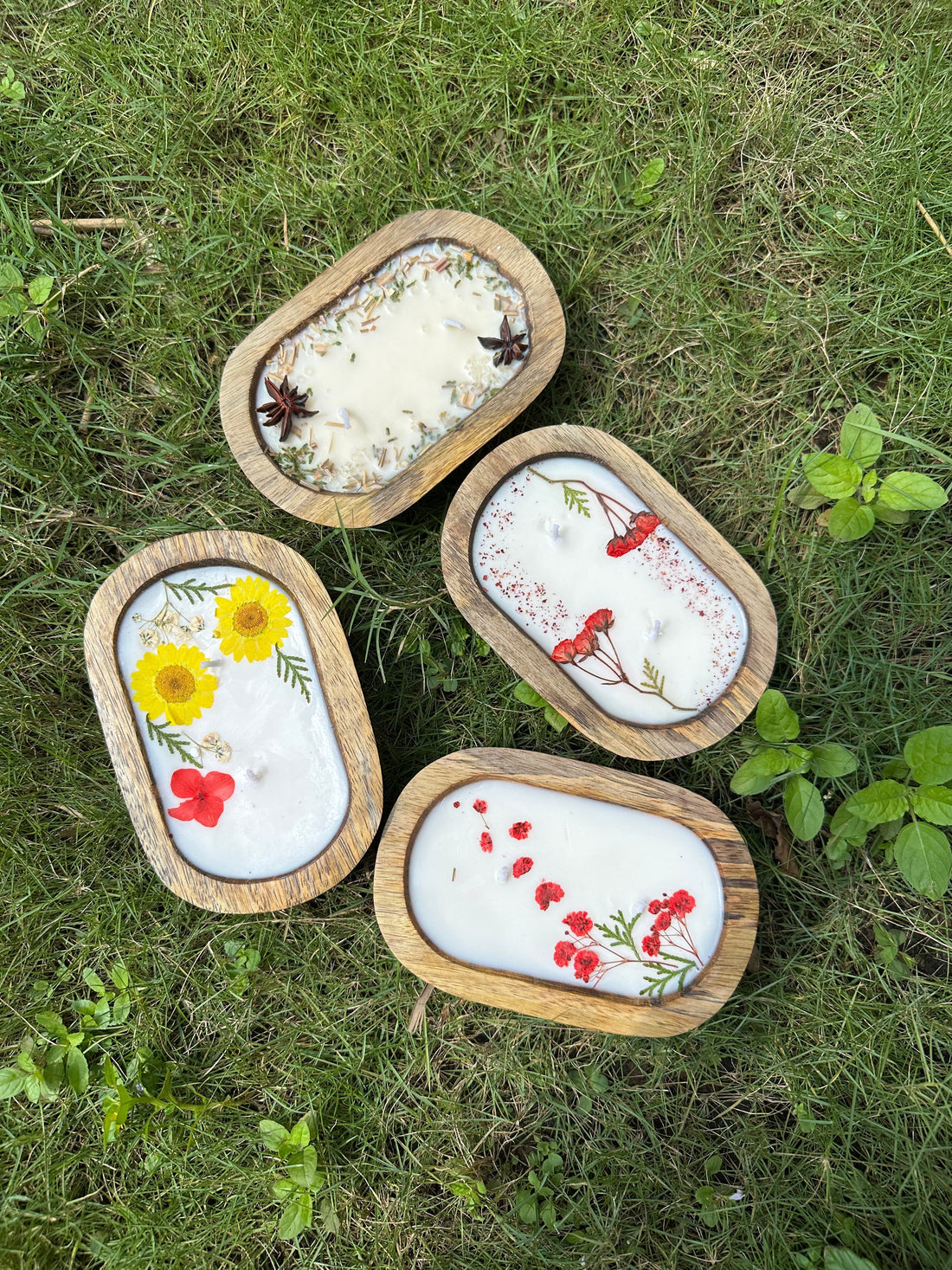 Four wooden bowl candles with each decorated with different floral, fruity, botanical decor