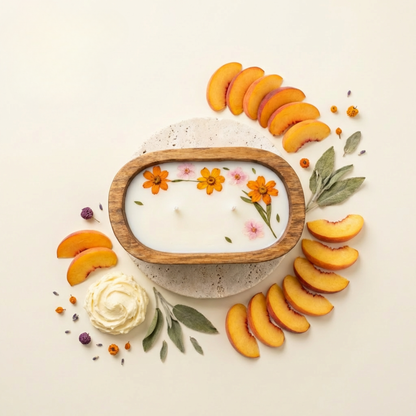 Candle with floral design surrounded by sliced peaches and decorative elements on a light background
