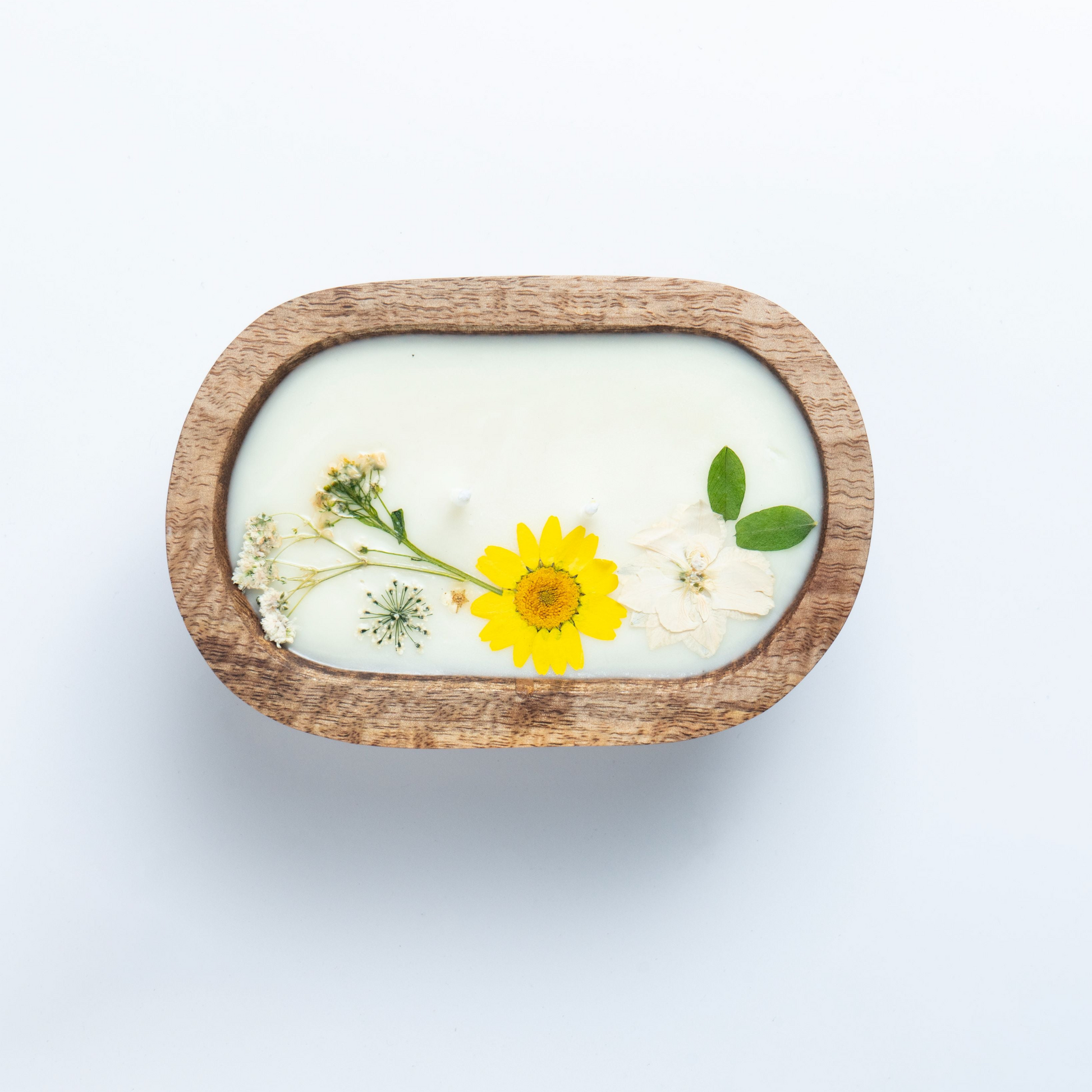 Bar of soap with a wooden casing and embedded yellow flower on a white background
