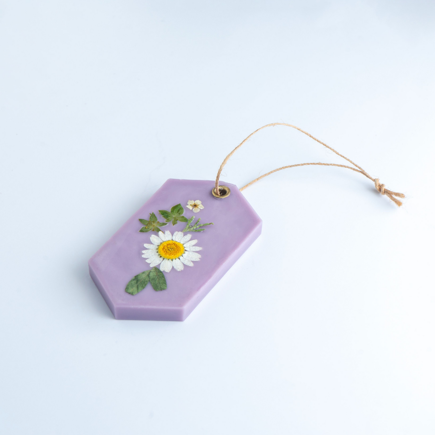 Hexagonal purple decorative item with pressed flowers on a light blue background