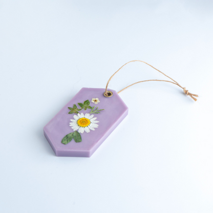 Hexagonal purple decorative item with pressed flowers on a light blue background