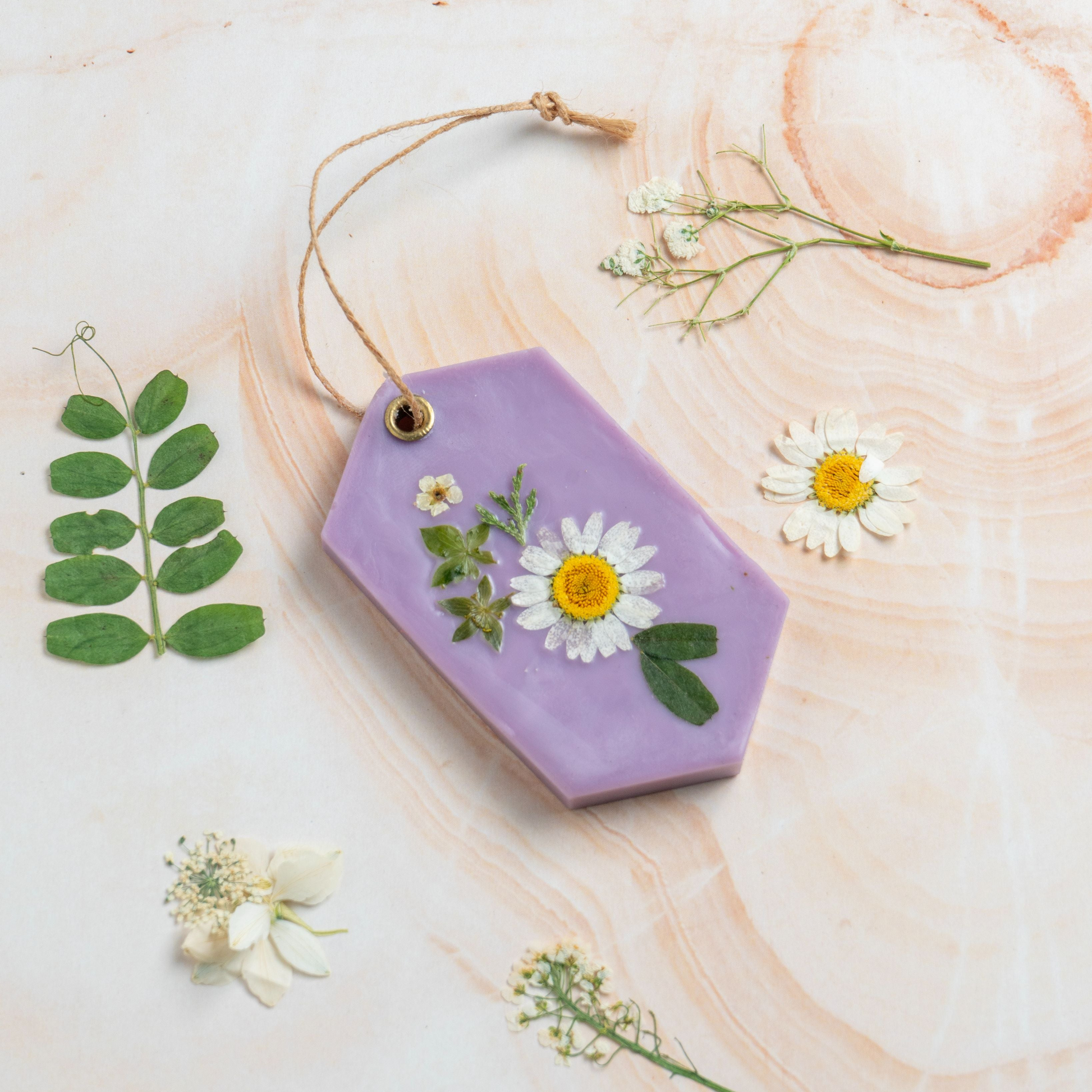 Hexagonal purple ornament with pressed flowers on a light wooden surface
