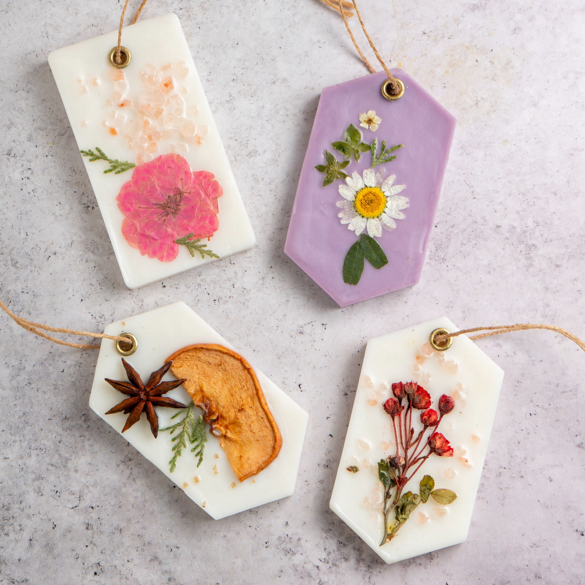 Four decorative soap tags with floral and botanical designs on a gray surface.