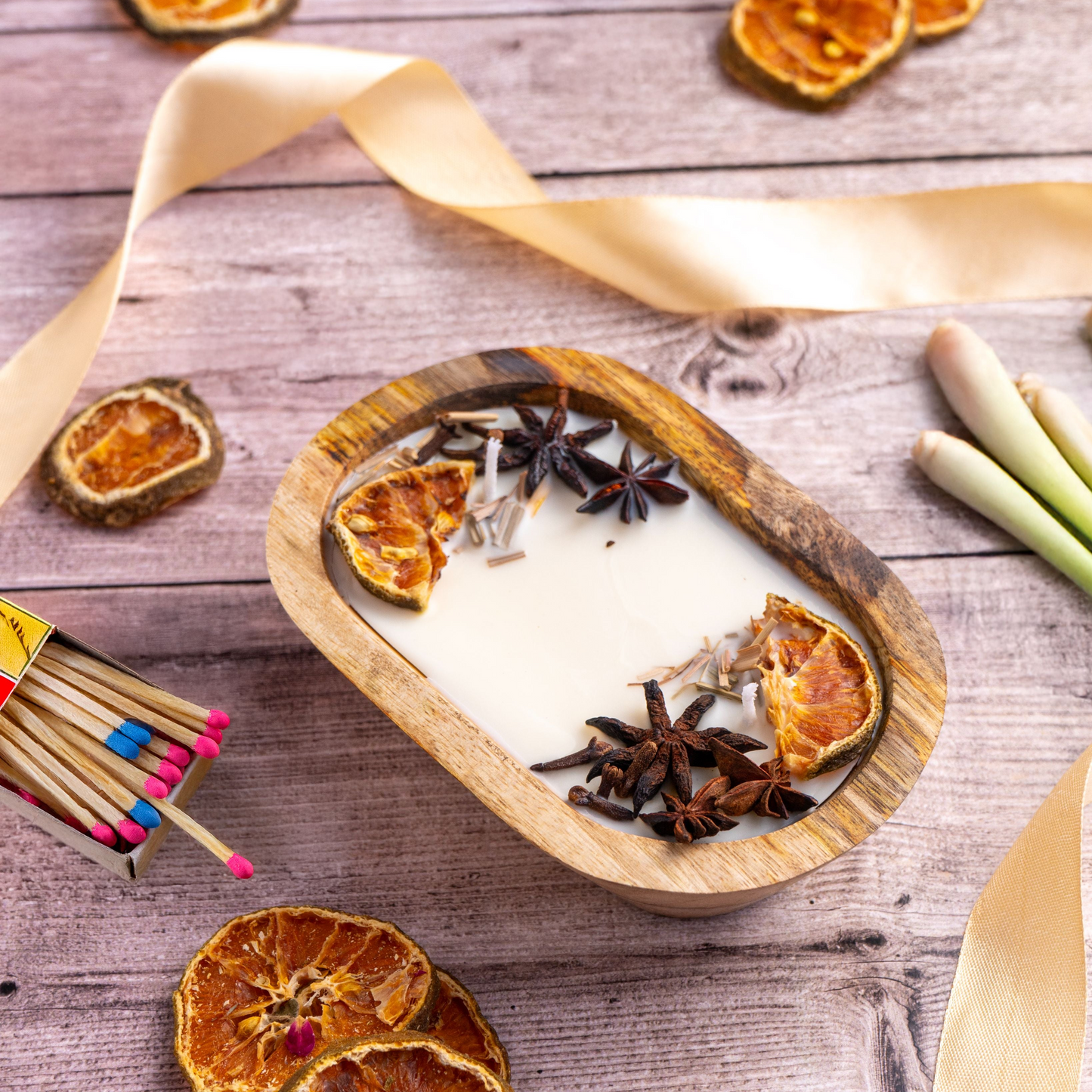 Heart-shaped candle with dried oranges and star anise on a wooden surface