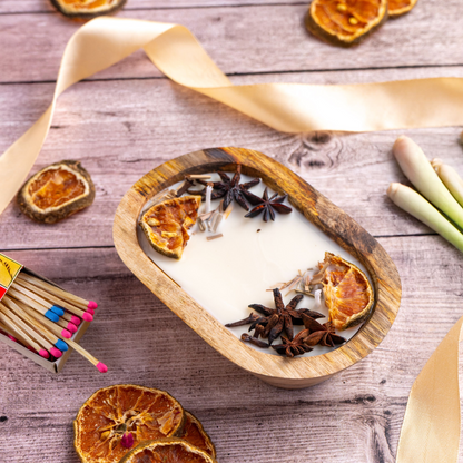 Heart-shaped candle with dried oranges and star anise on a wooden surface