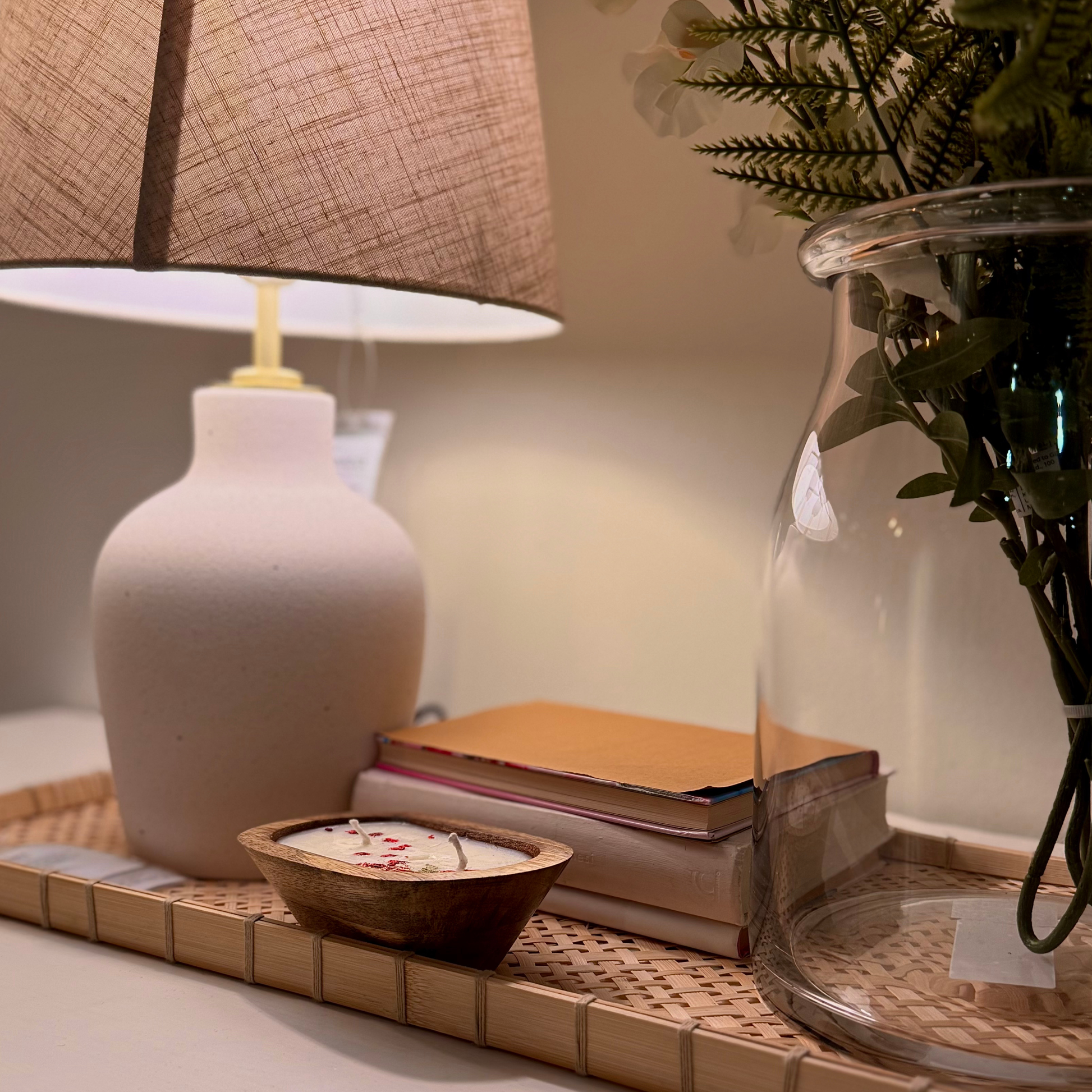 Decorative items including a lamp, books, a wooden bowl candle, and a vase on a table.