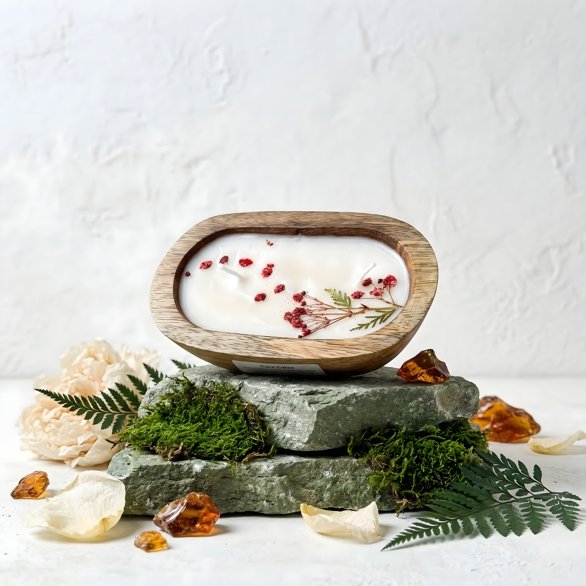 Decorative candle with natural elements on a stone base against a white background