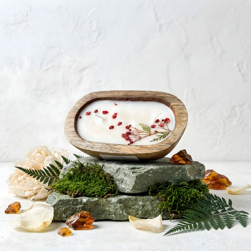 Decorative candle with natural elements on a stone base against a white background
