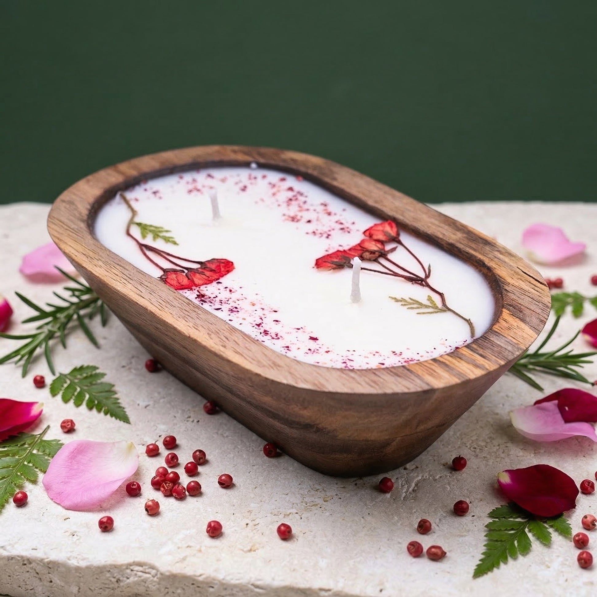 Candle in a wooden holder with floral decorations on a stone surface.