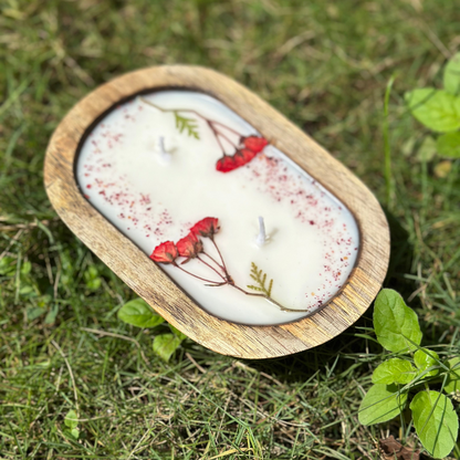 Candle with natural elements in a wooden holder on grass