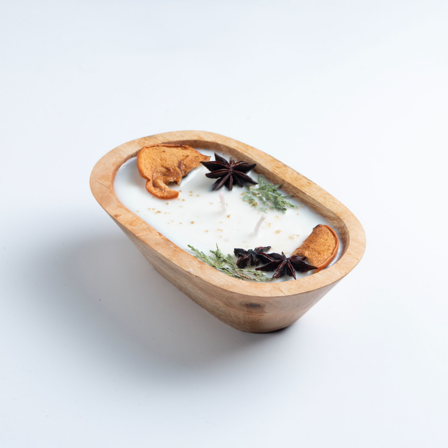 Candle in a wooden dish with star anise and cinnamon on a white background