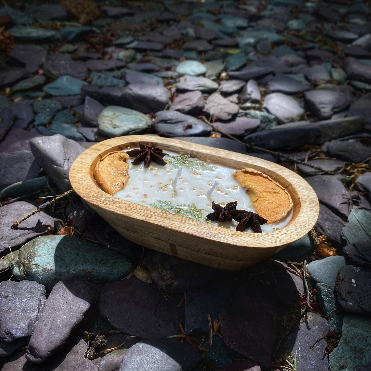 Wooden bowl with a white substance and star anise on a bed of stones