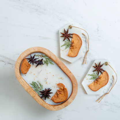 Decorative items with dried orange slices, star anise, and green leaves on a white surface.