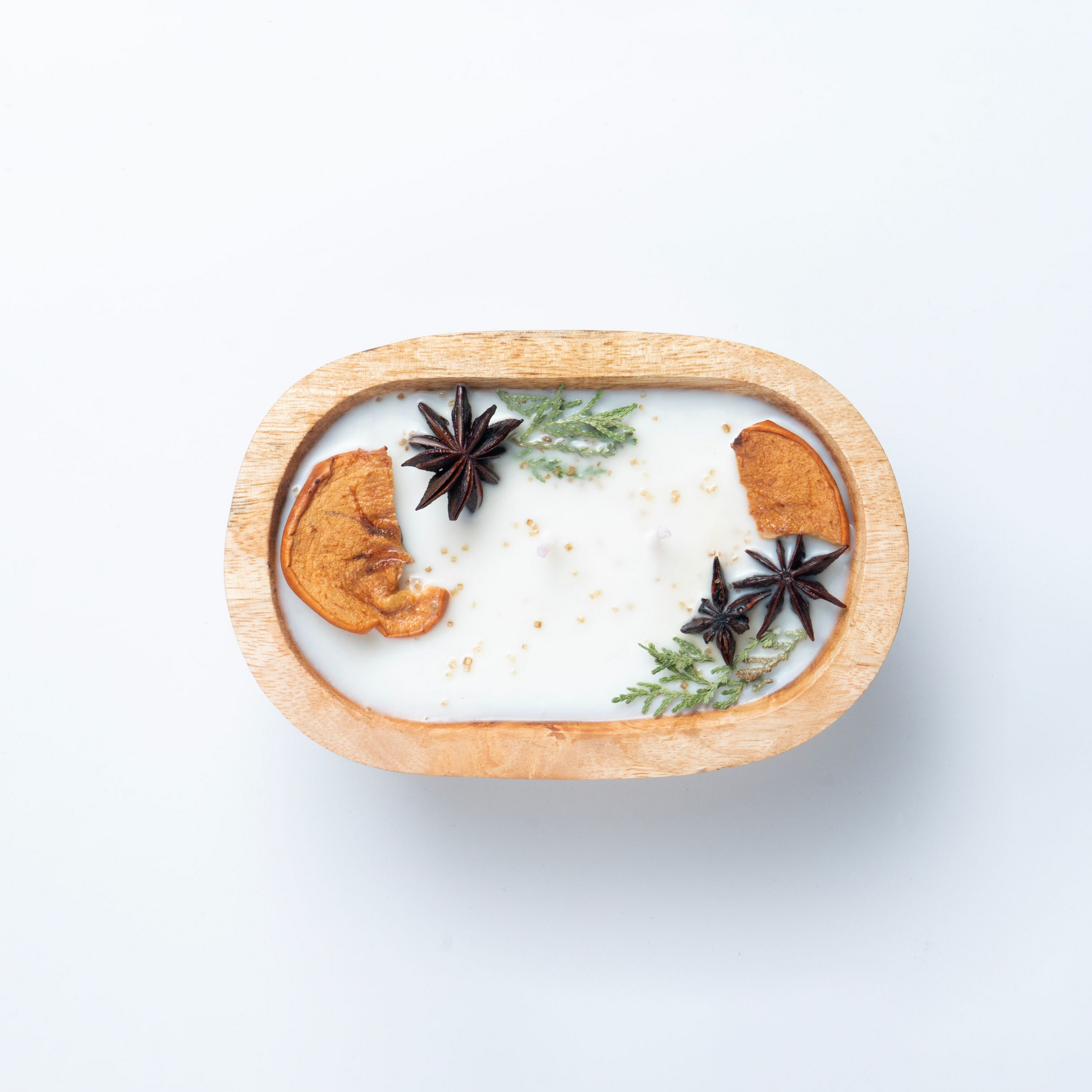 Decorative candle with cinnamon sticks and star anise in a wooden holder on a white background