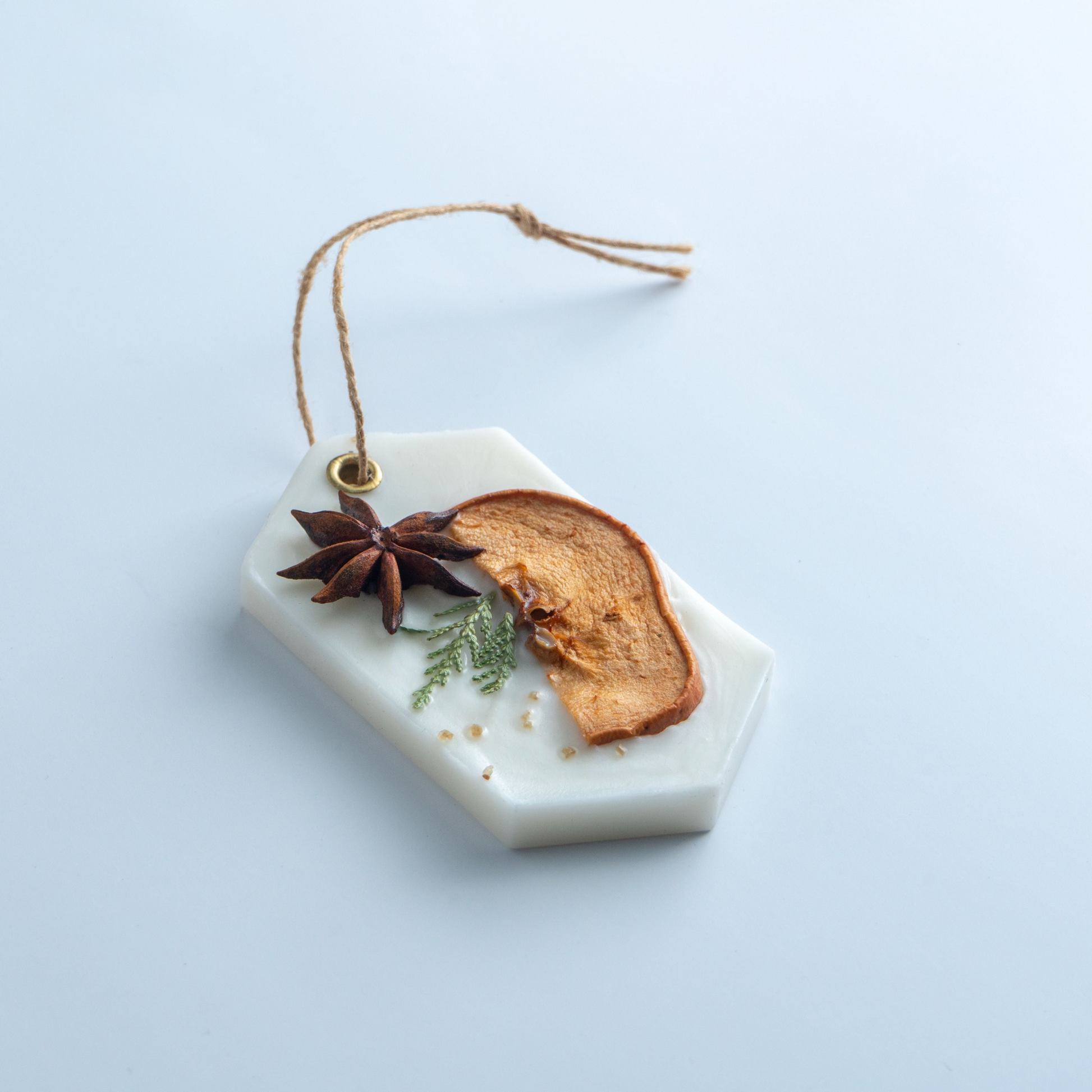 Decorative hanging ornament with dried fruit and spices on a light blue background