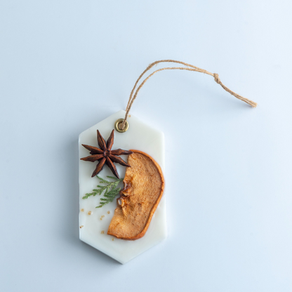 Decorative hanging tag with dried elements on a light blue background