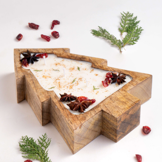 Wooden Christmas tree-shaped tray with bath salts, star anise, and cranberries on a white background