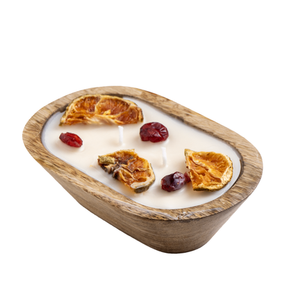 A wooden bowl candle with dried fruits against a white background