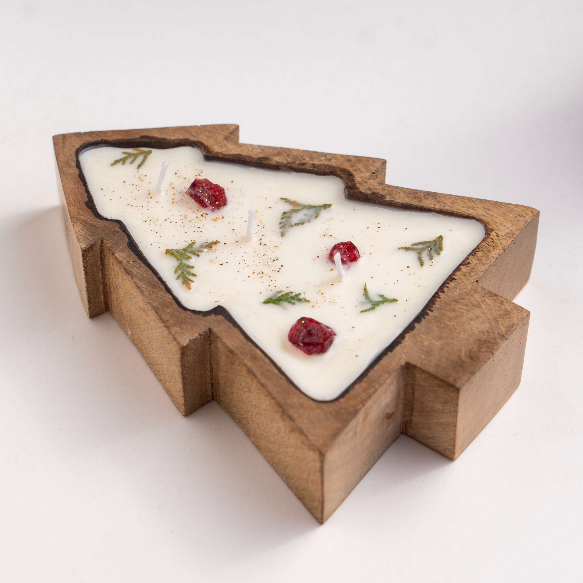 Wooden tray shaped like a Christmas tree with a white surface, garnished with red berries and green leaves on a white background.