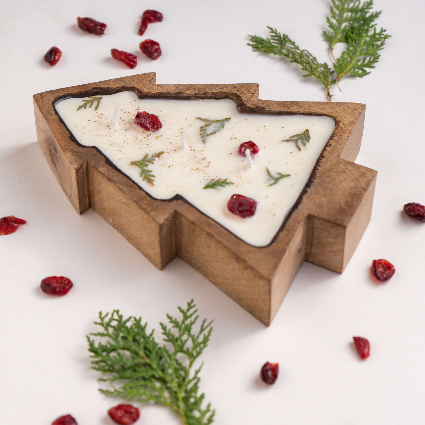 Wooden mold shaped like a Christmas tree with white chocolate and cranberries on a light background.