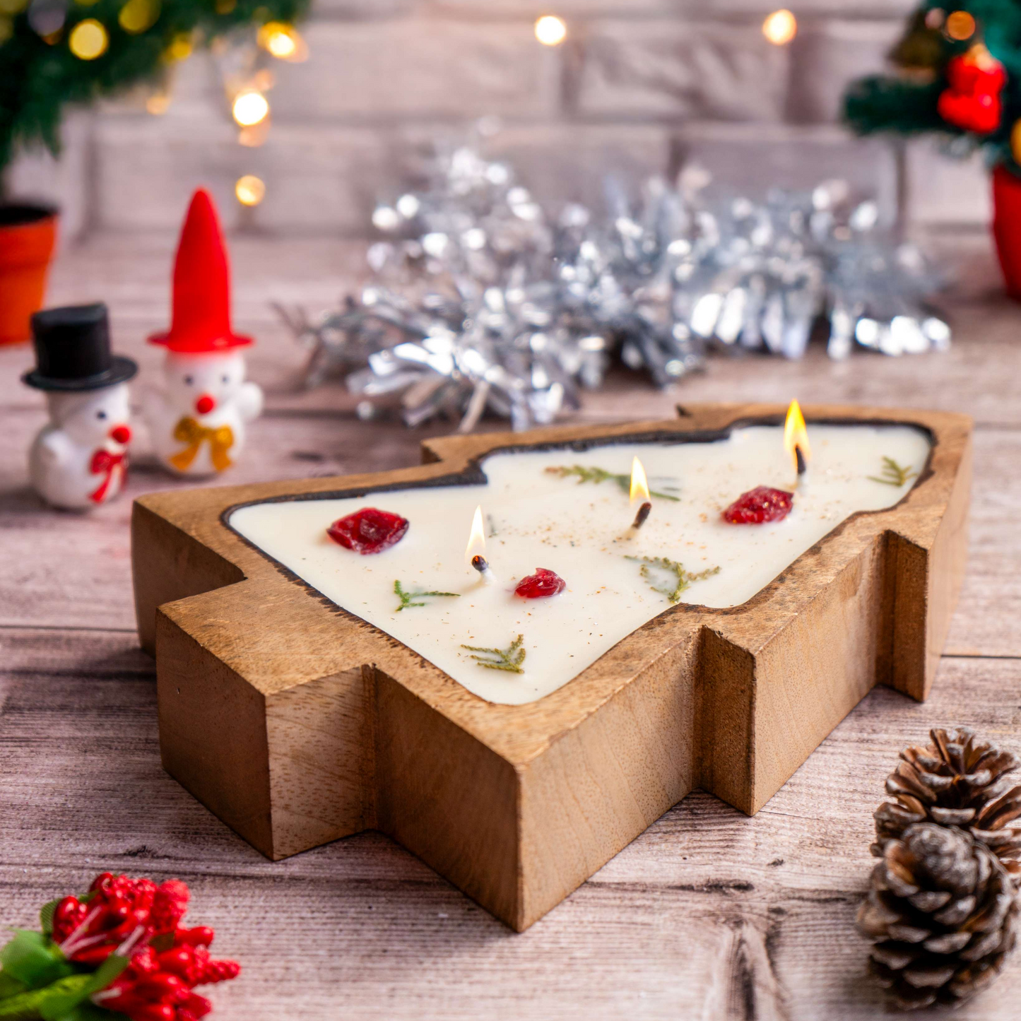 Decorative candle with Christmas-themed decorations on a wooden surface.