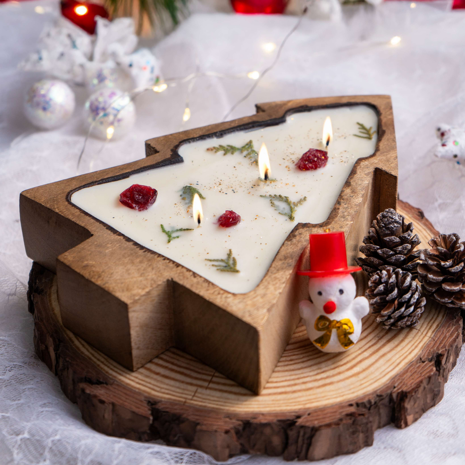 Decorative candle with wooden holder and festive decorations on a white surface