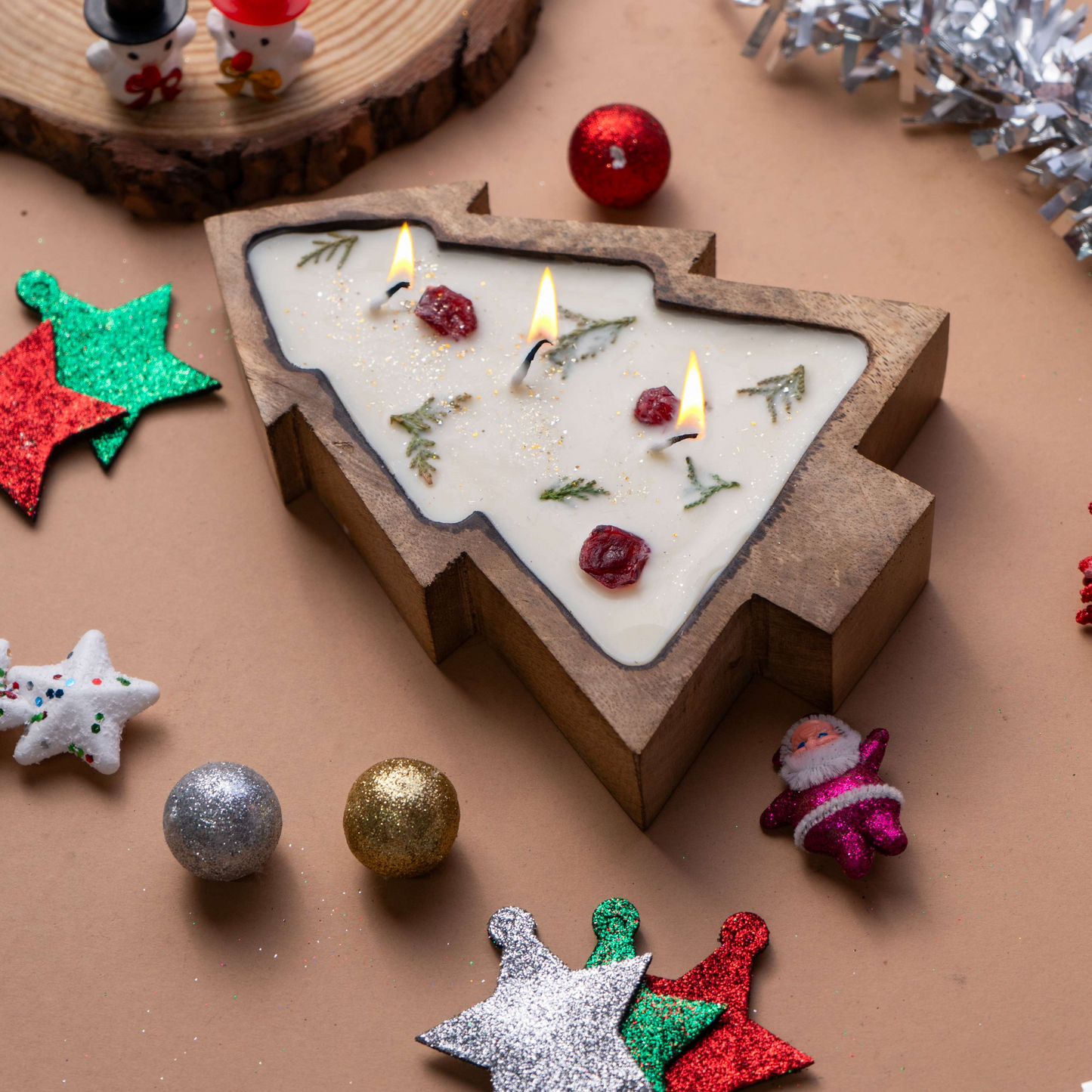 Christmas-themed candle shaped like a tree with decorative ornaments on a brown surface