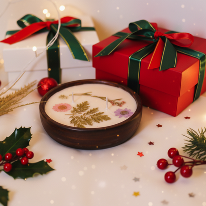 Decorative soap with pressed flowers, surrounded by Christmas-themed elements on a white surface.