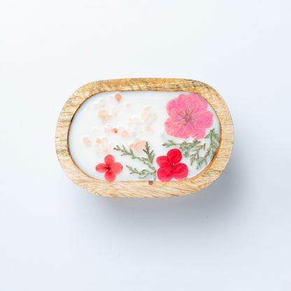 Candle with floral design in a wooden holder on a white background