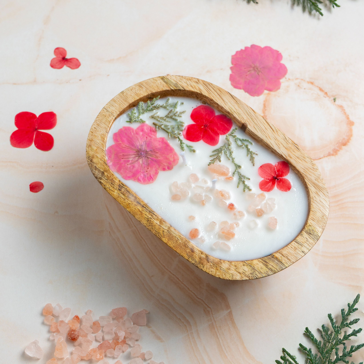 Wooden bowl with floral bath salts on a light wooden surface