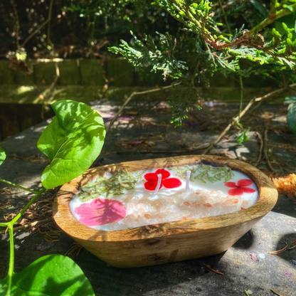 Wooden bowl with floral design on a stone surface with greenery in the background