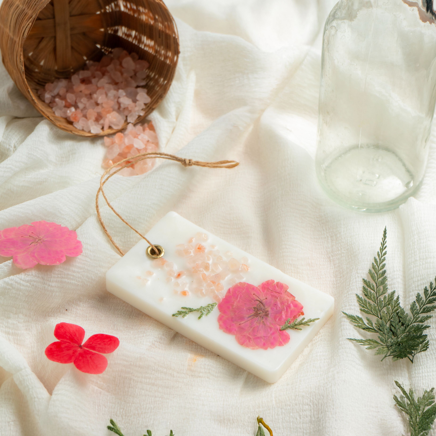 Handmade soap with floral design on a white fabric background with bath salts and a jar.