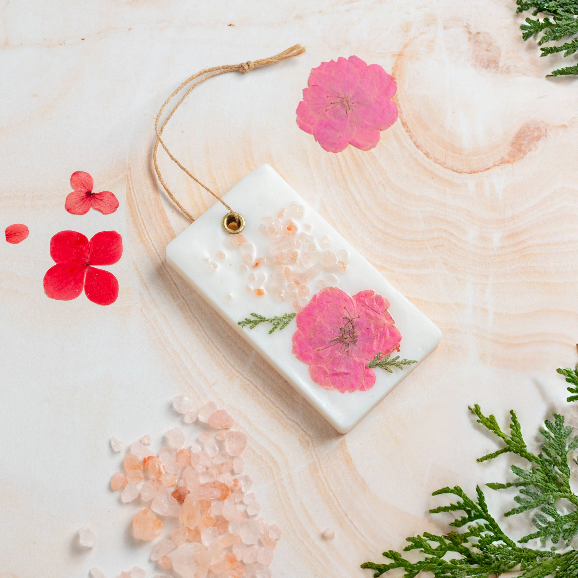 Bar of soap with floral design on a wooden surface with flowers and leaves.