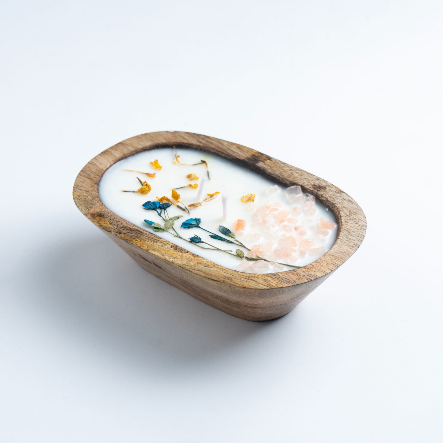 Wooden bowl with a white candle inside on a light gray background