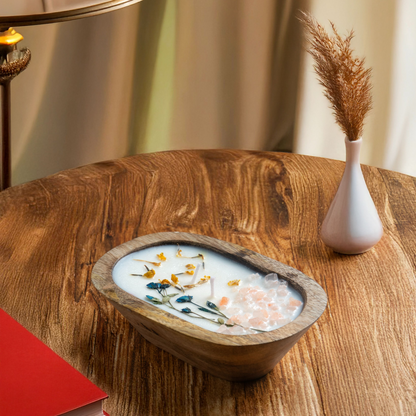 Decorative bowl with flowers on a wooden table next to a lamp and vase.
