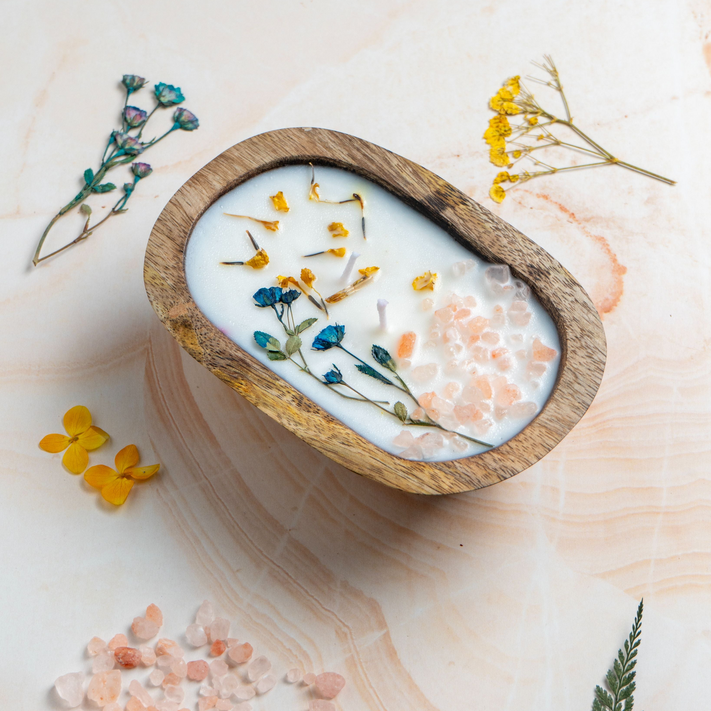 Wooden bowl with a candle and dried flowers on a light wooden surface